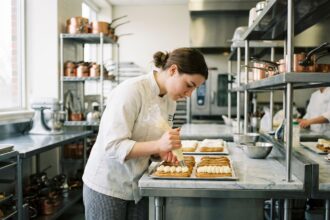 Jeune femme en cuisine décorant des éclairs avec précision